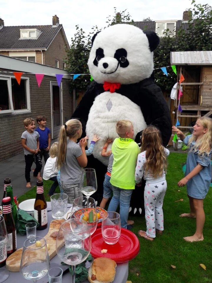 Panda mascotte omringd door kinderen tijdens een kinderfeestje in de tuin