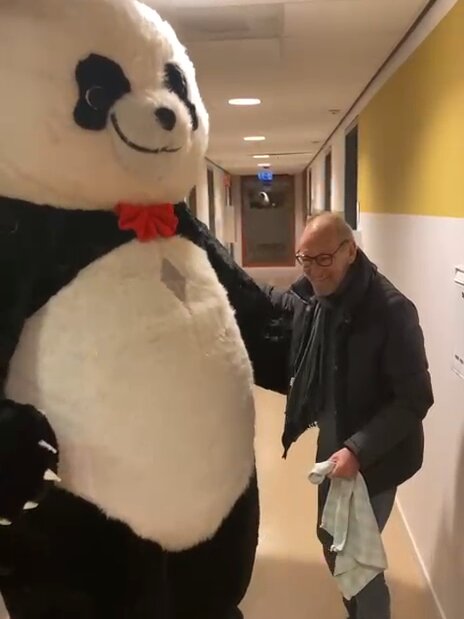 Panda mascotte in gesprek met een bewoner in de gang van een zorginstelling